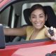 New driver smiling and holding car keys from the driver seat
